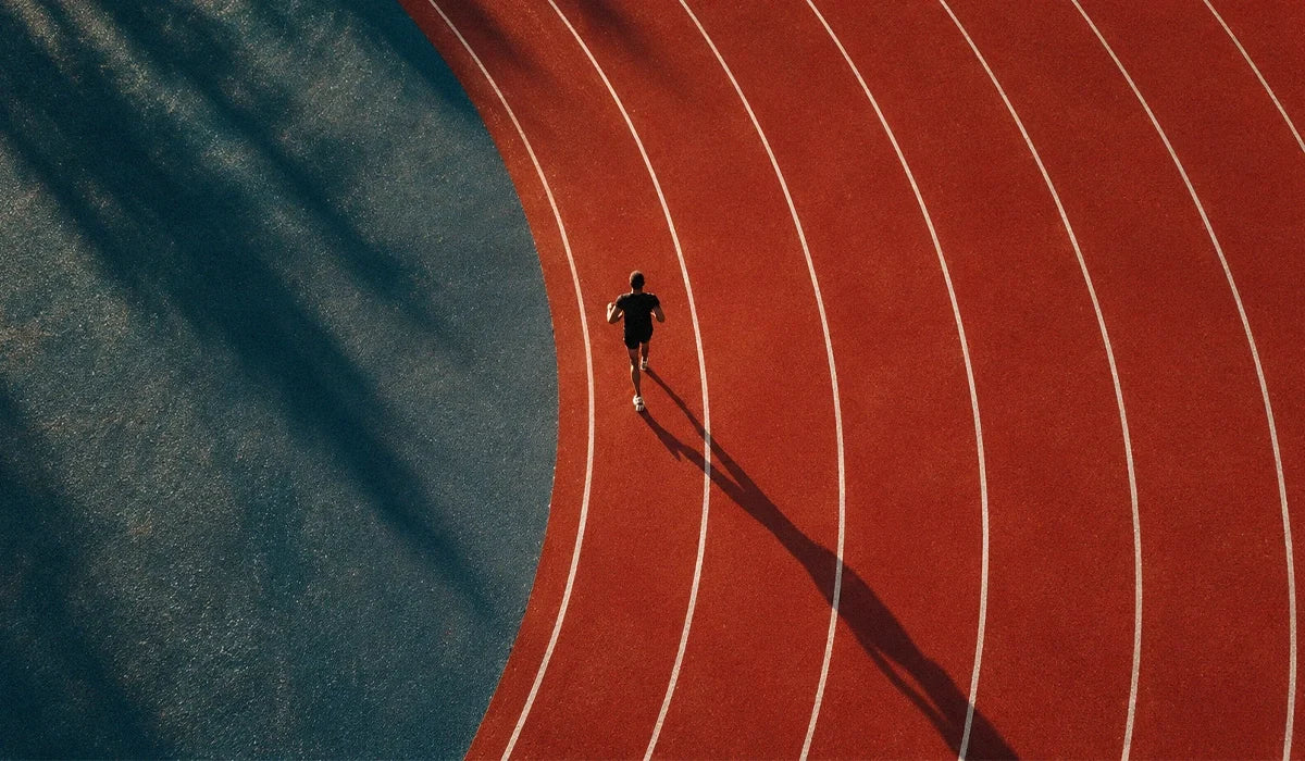 Runner stretching on a path beside a shaker of beetroot-coloured drink