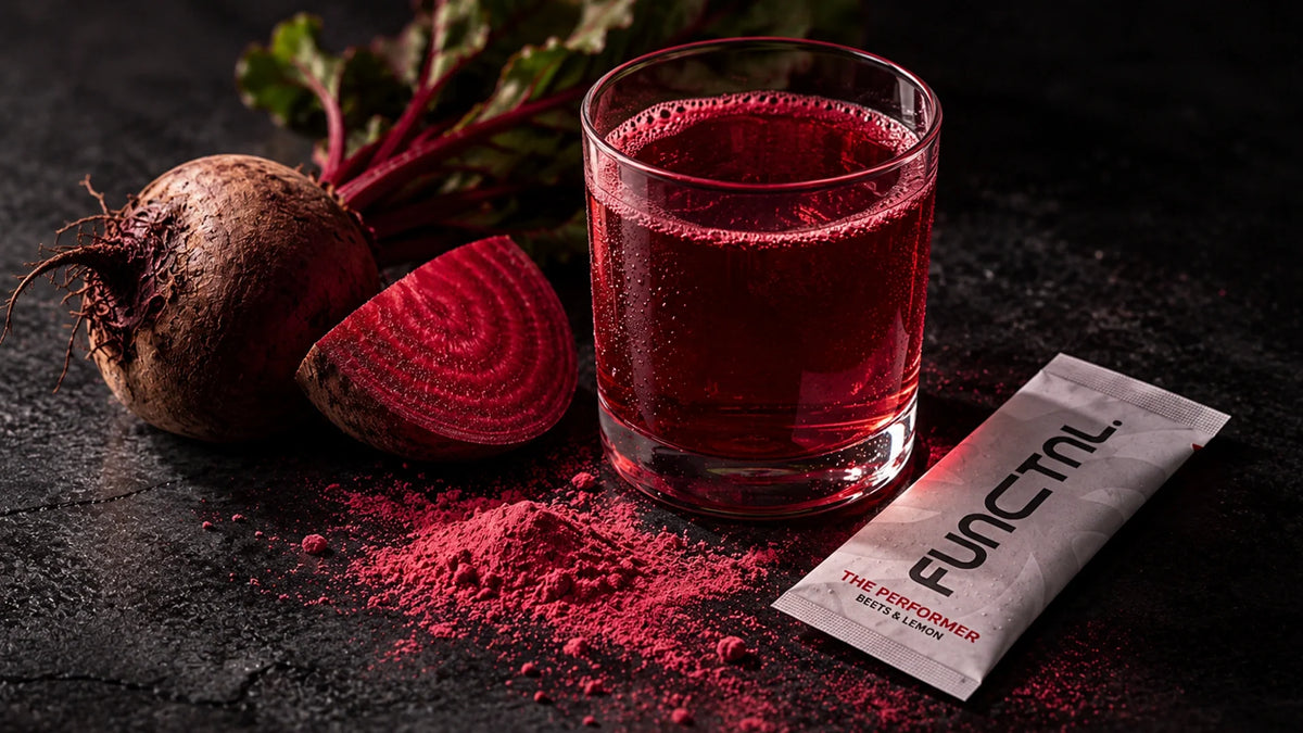 Beetroot-coloured drink in a glass beside fresh beetroot and a sachet of powder